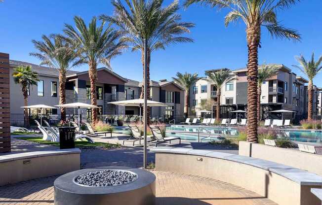A sunny day at a resort with palm trees and a fire pit.