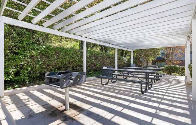 A white pergola with a bench and mailbox underneath it.