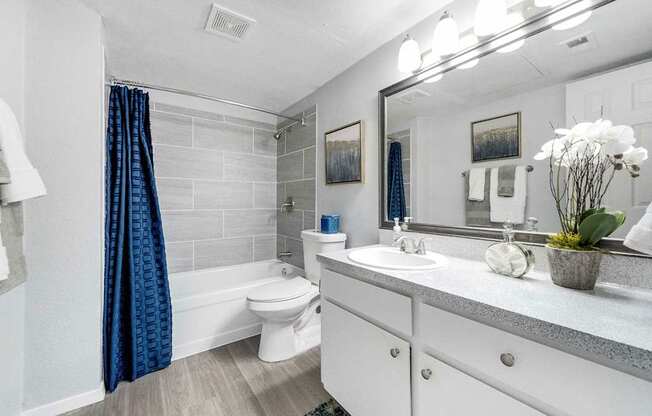 a white bathroom with a blue shower curtain and a toilet