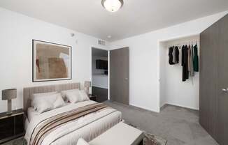 A bedroom with a bed, a painting, a wardrobe, and a chair.