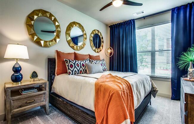 Grant Prairie TX Apartments- Spacious Bedroom With Cozy Gray Carpets, Stylish Ceiling Fan, and Large Open Window