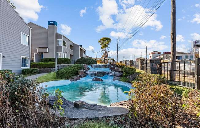 a small pool with waterfalls in front of apartment buildings