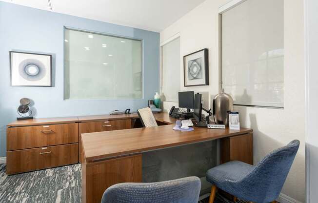 A room with a desk, chairs and a phone.