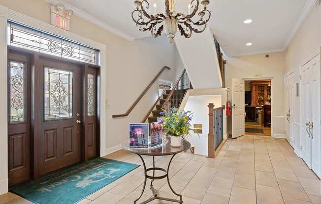 the entryway of a house with wooden doors and a chandelier