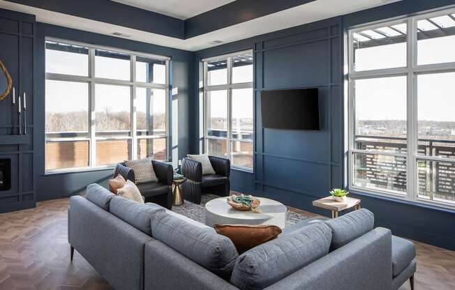 A grey couch is in front of a large window in a room with a fireplace.