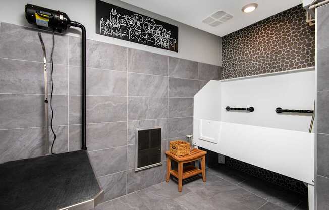 A bathroom with a white tub and grey tiles.