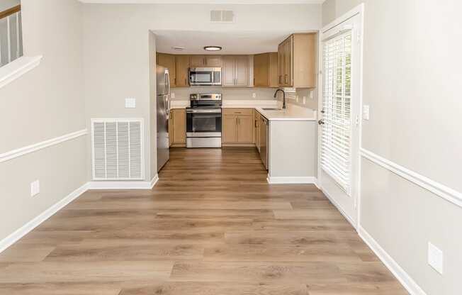 empty living room with wood flooring leading to a kitchen