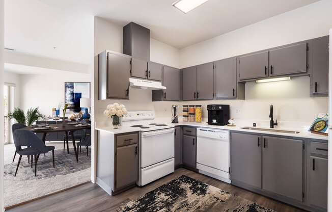 L-shaped kitchen with white appliances, gray cabinets and the dining room behind.at Shoreline Village, Richland