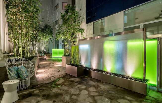 A modern outdoor space with a stone floor, a white chair, and a green lighted wall.