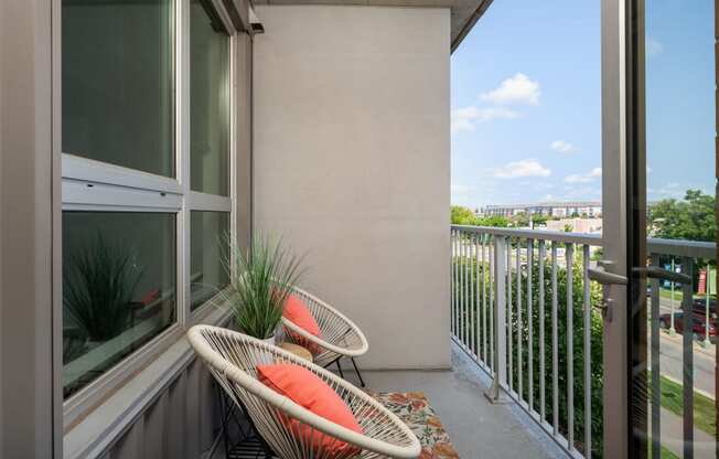 a balcony with two chairs and a view of the city