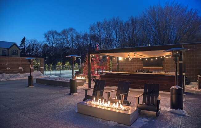 Outdoor patio with firepit, bar, and seating in the winter time at The McMillan