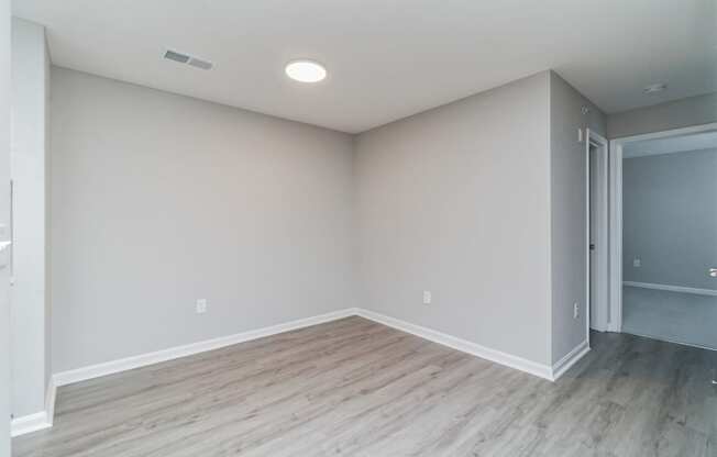 an empty living room with wood floors and grey walls