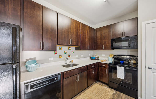 A kitchen with dark wood cabinets and black appliances.