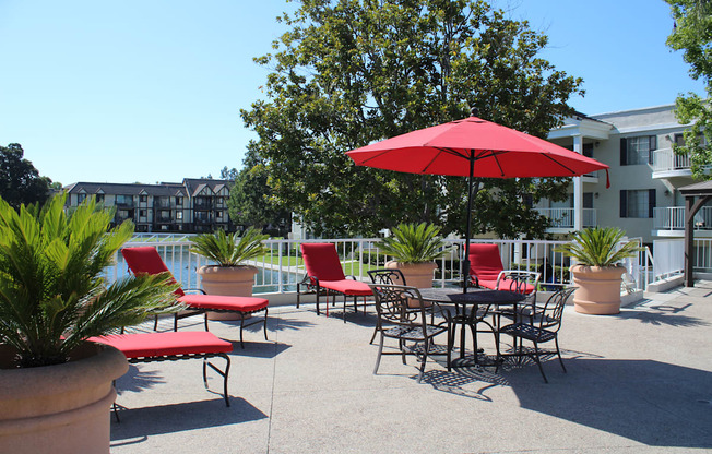 A red umbrella is in front of a table and chairs.