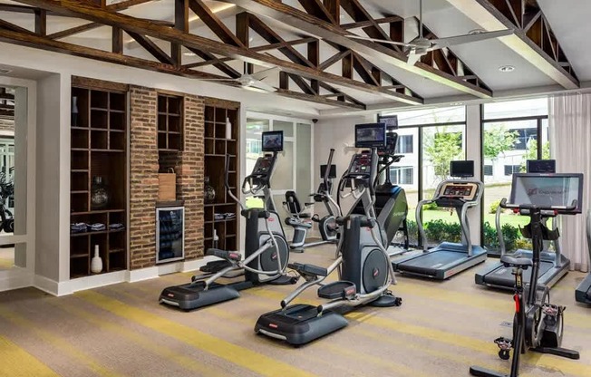 A gym with a variety of exercise equipment including treadmills, stationary bikes, and elliptical machines.