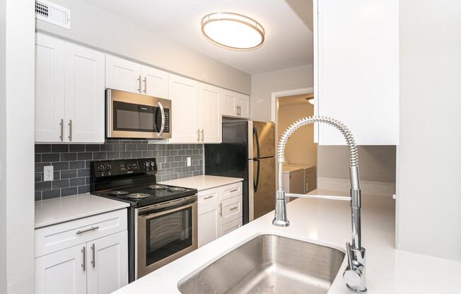 a kitchen with white cabinets and black appliances and a sink