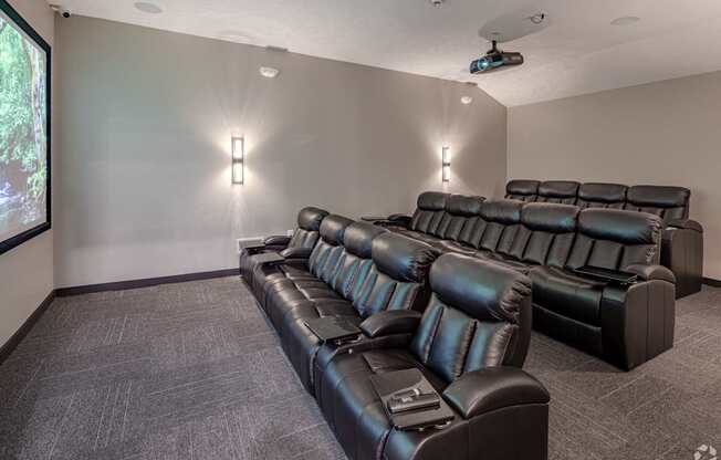 A black leather sofa in a room with a projector screen.