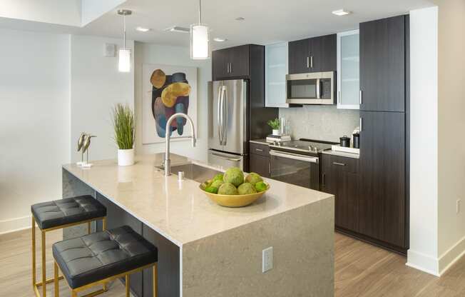 a kitchen with a large island with a bowl of fruit