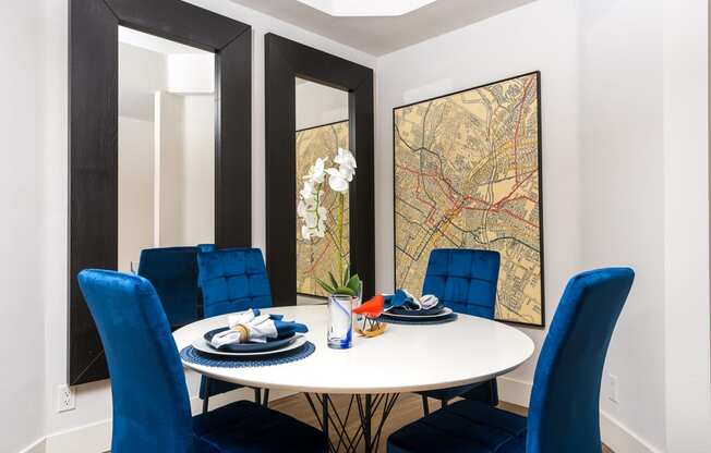 a dining room with a white table and blue chairs and a map on the wall