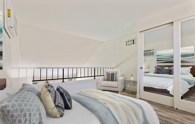 Sleeping area of an executive loft with mirrored closet doors, wood style floors