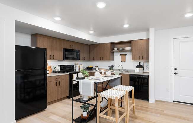 a kitchen with black appliances and a white table with two stools at QUINN BY VINTAGE, Shoreline, Washington