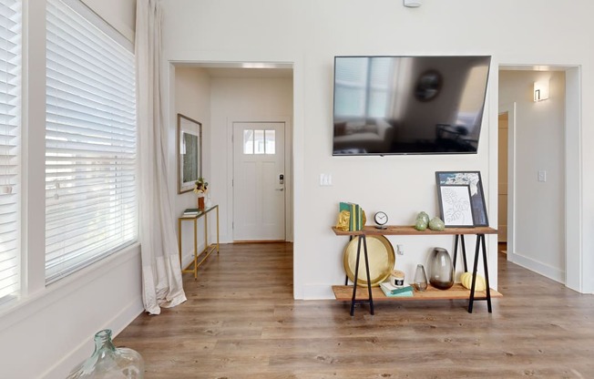 a living room with a tv on the wall and a wooden floor