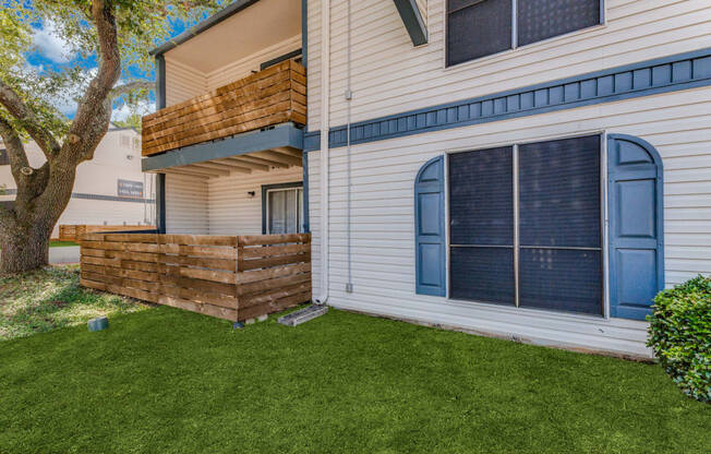 a backyard with green grass and a white house with a blue door