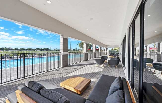 a living room with a couch and a balcony overlooking a swimming pool