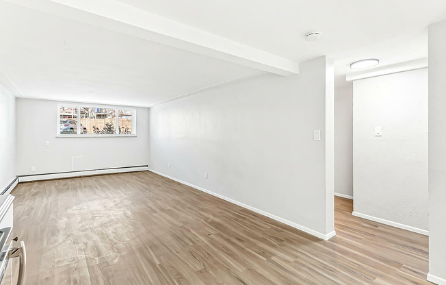 Bright, spacious room with modern wood flooring and large window offering natural light in a contemporary apartment.