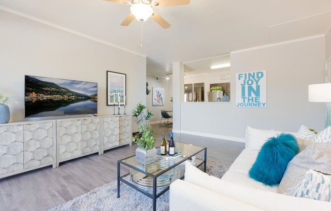 a living room with white furniture and a ceiling fan