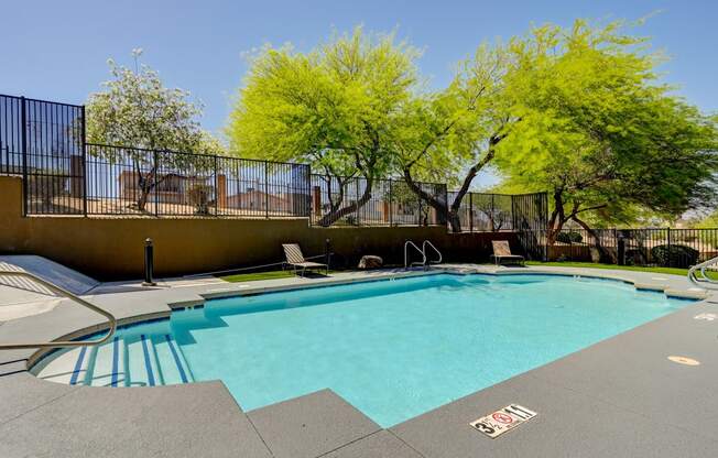 a swimming pool with a fence around it and trees in the background