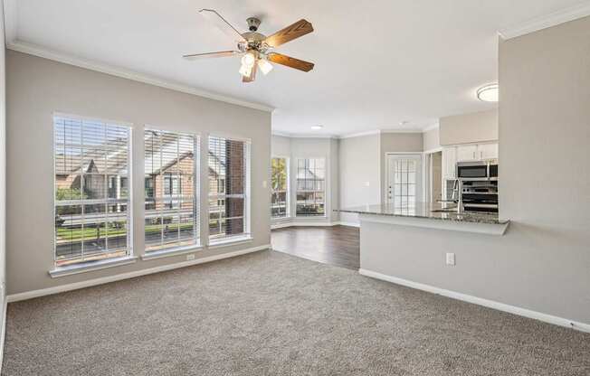 A spacious room with a ceiling fan and large windows.