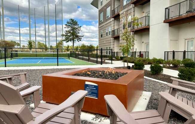 A fire pit in the middle of a patio surrounded by chairs.