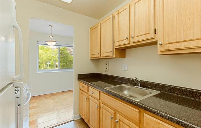 kitchen with tile flooring, refrigerator, gas stove, oak cabinetry, and view of dining area at chillum place apartments in lamond riggs washington dc