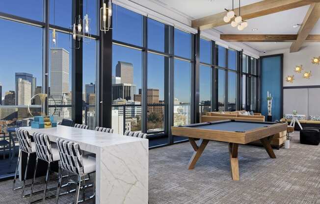 Sky lounge with granite table, pool table and large glass windows with view of Denver skyline