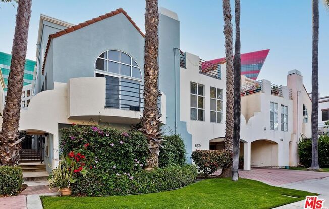 a blue and white house with palm trees in front of it