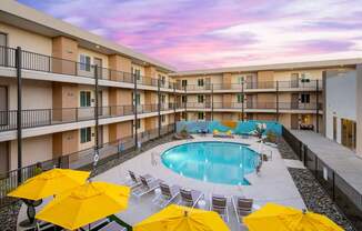 A pool surrounded by yellow umbrellas and chairs.