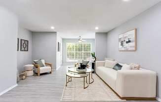 A living room with a white couch, a coffee table, and a window with blinds.