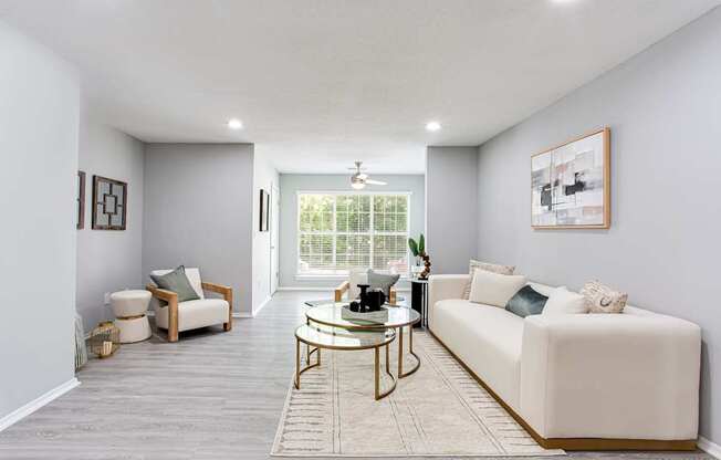 A living room with a white couch, a coffee table, and a window with blinds.