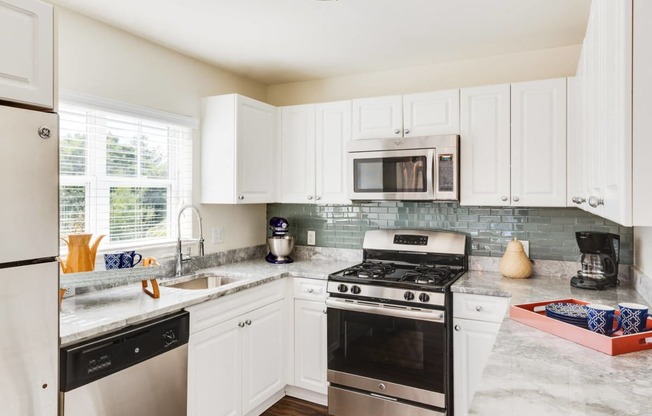 a kitchen with stainless steel appliances and white cabinets at Residences at Stevens Pond, Saugus, 01906