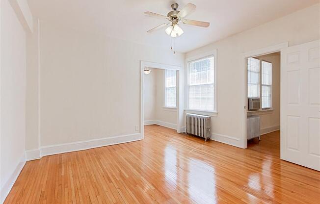 vacant living area with hardwood flooring, ceiling fan, and large windows at parkside apartments in washington dc