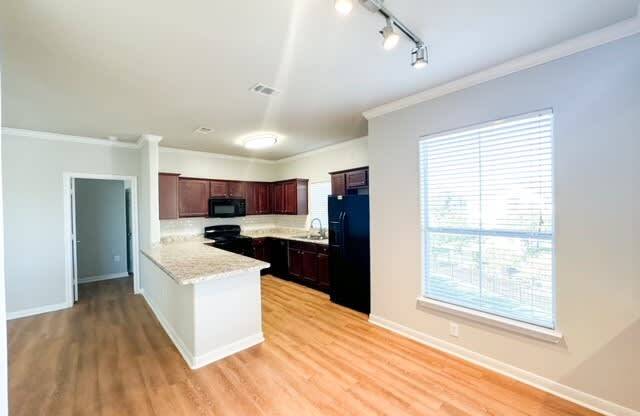 an empty kitchen with wood floors and a large window