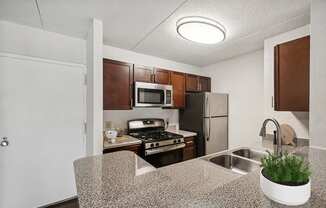 Model Kitchen with Dark Wood Cabinets & Wood-Style Flooring at Mason Van Dorn Apartments located in Alexandria, VA.