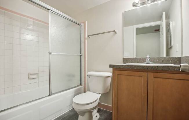 A white toilet sits in a bathroom next to a glass shower door.