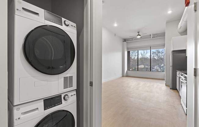 A modern laundry room with a washer and dryer stacked on top of each other. at Brickside Heights, Utah