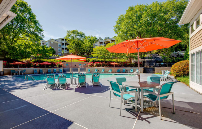 a patio with a pool and tables with umbrellas