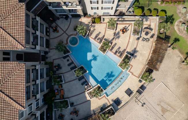 A swimming pool surrounded by a sandy area and a building.