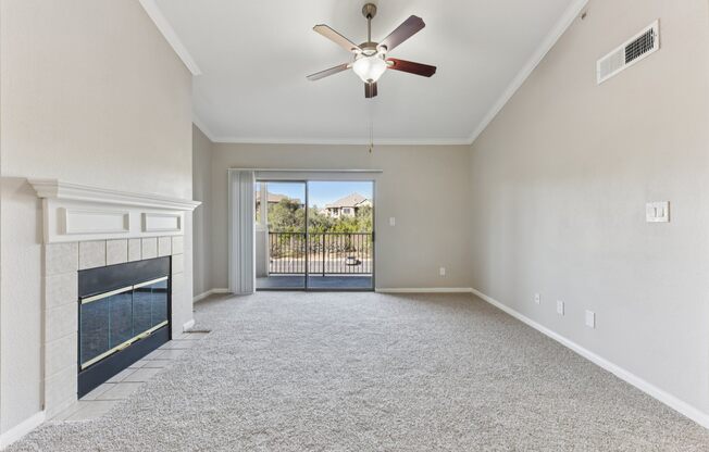 A spacious room with a fireplace and a ceiling fan.