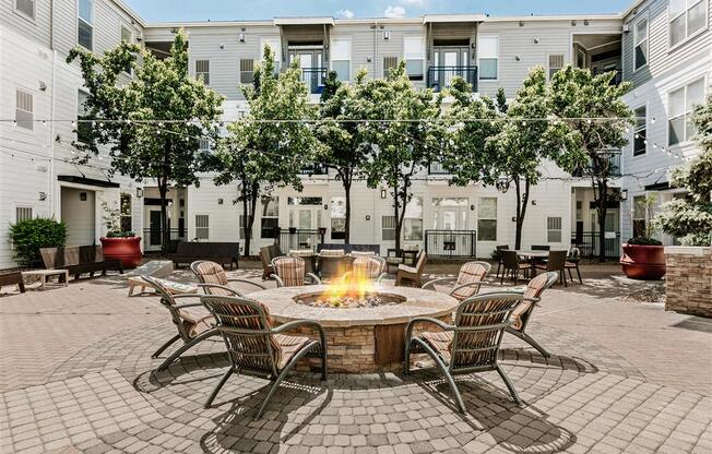 a fire pit in the middle of a patio with chairs and tables