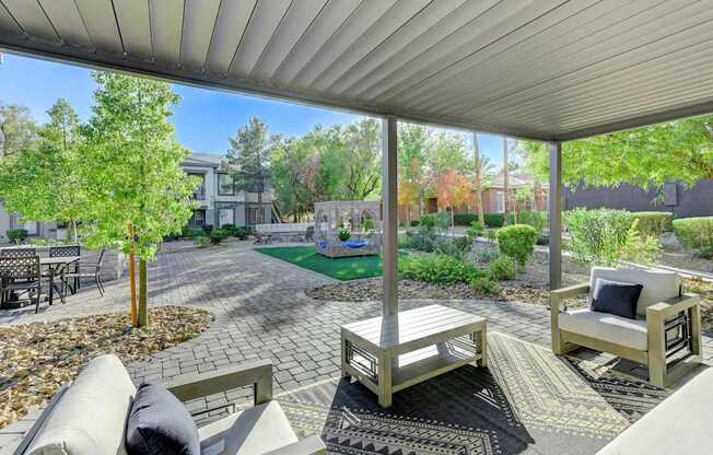 A patio with a couch, chairs, and a table with a pillow on it.